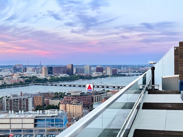 balcony at dusk featuring a water view