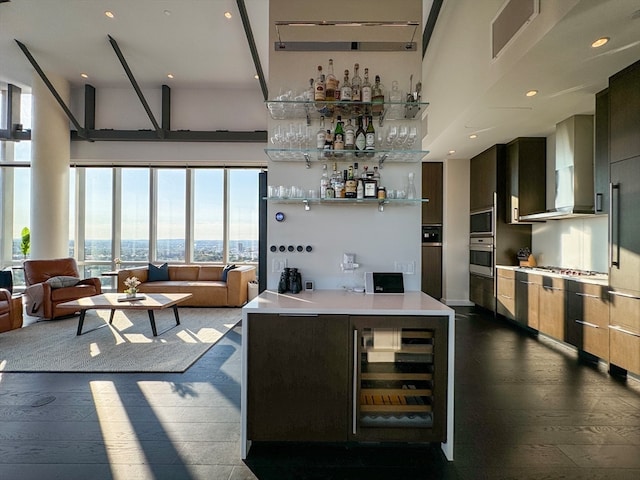 kitchen featuring stainless steel appliances, dark hardwood / wood-style floors, wall chimney exhaust hood, wine cooler, and a high ceiling