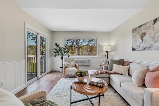 living room featuring a wainscoted wall, wood finished floors, and a wall mounted air conditioner