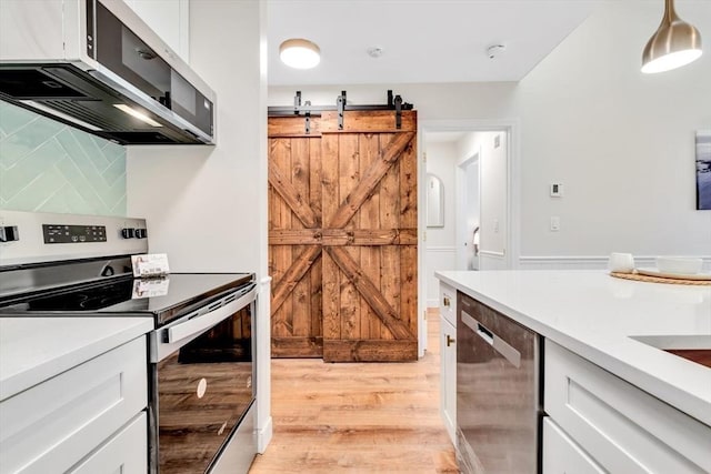 kitchen featuring appliances with stainless steel finishes, light wood finished floors, white cabinets, and light countertops