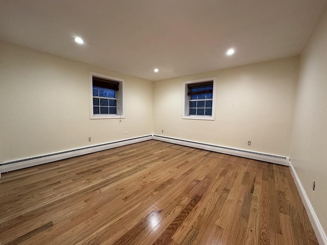 empty room with recessed lighting, a baseboard radiator, baseboards, and wood finished floors