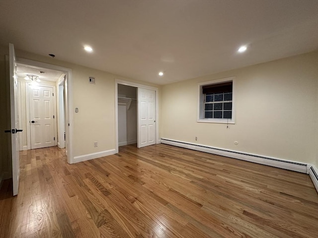 unfurnished bedroom with recessed lighting, baseboard heating, and wood finished floors
