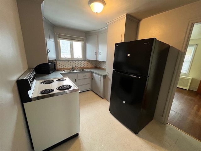 189 Bush St, Fall River, MA 02724 - kitchen with white electric stove, freestanding refrigerator, a sink, tasteful backsplash, and light floors