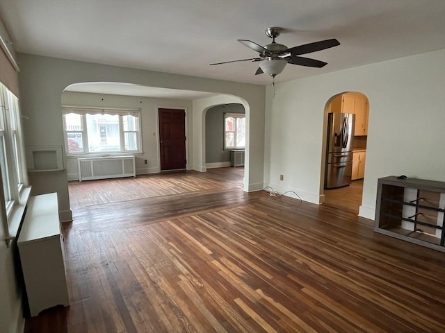 189 Bush St, Fall River, MA 02724 - unfurnished living room featuring radiator, arched walkways, a ceiling fan, and dark wood-style flooring