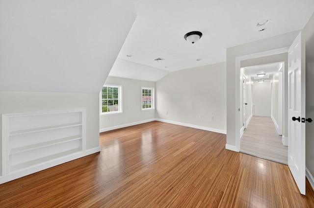 70 Hancock St, Whitman, MA 02382 - unfurnished living room featuring built in shelves, vaulted ceiling, and wood finished floors