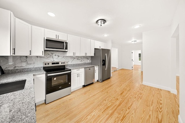 70 Hancock St, Whitman, MA 02382 - kitchen with appliances with stainless steel finishes, white cabinetry, backsplash, light wood-style flooring, and light stone countertops