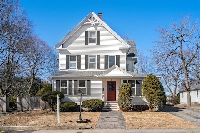 view of front of property featuring a chimney, a shingled roof, and fence