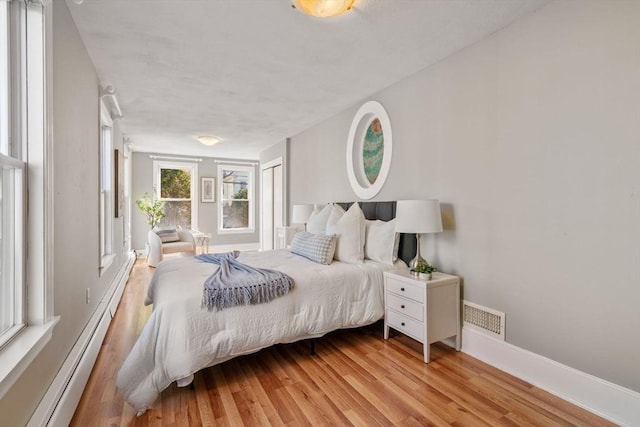 bedroom featuring visible vents, baseboards, light wood-style flooring, and a baseboard radiator