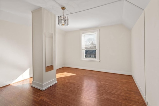 interior space featuring an inviting chandelier, wood finished floors, baseboards, and vaulted ceiling