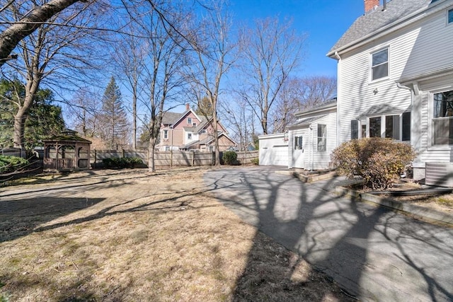 view of yard with fence, aphalt driveway, a residential view, a gazebo, and a garage