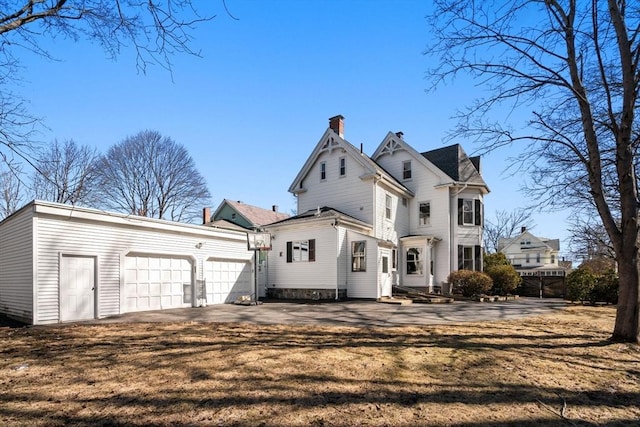 back of property with a garage, a yard, a chimney, and entry steps