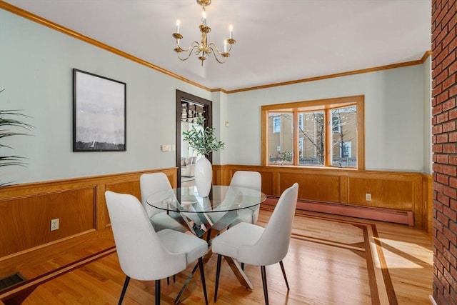 dining area featuring a wainscoted wall, light wood-type flooring, a baseboard heating unit, and an inviting chandelier