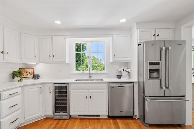 21 Johnson Rd, Winchester, MA 01890 - kitchen with appliances with stainless steel finishes, wine cooler, a sink, light countertops, and white cabinetry