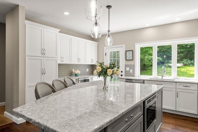 172 Carolyn Cir, Marshfield, MA 02050 - kitchen with stainless steel appliances, backsplash, white cabinetry, a center island, and light stone countertops