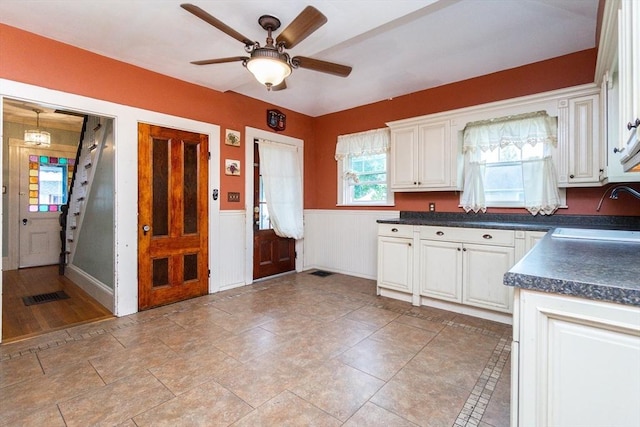 13 Mullin Ave, Quincy, MA 02169 - kitchen featuring dark countertops, ceiling fan, white cabinetry, and wainscoting
