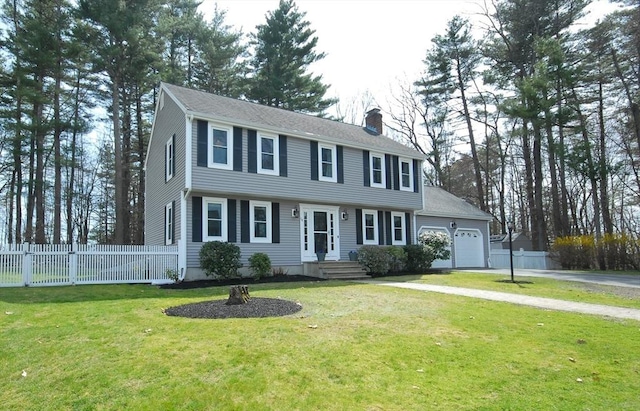 colonial home featuring fence, an attached garage, a front lawn, aphalt driveway, and a chimney