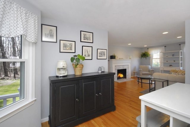 interior space featuring recessed lighting, a fireplace with flush hearth, and light wood-type flooring