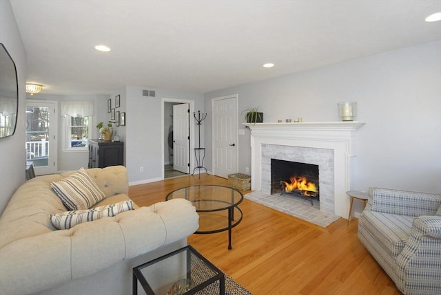 living area with visible vents, recessed lighting, light wood-style flooring, and a tile fireplace