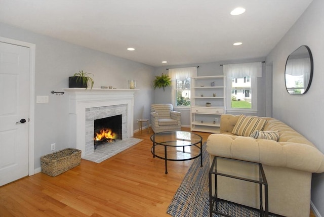 living room with light wood-style floors, baseboards, a lit fireplace, and recessed lighting