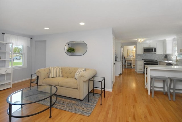 living area with light wood-style floors, baseboards, and recessed lighting