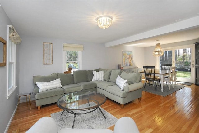 living area with baseboards, a notable chandelier, and light wood-style floors