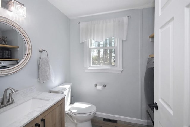 bathroom with baseboards, wood finished floors, toilet, and vanity