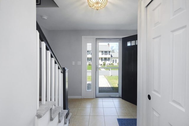entrance foyer with a healthy amount of sunlight, light tile patterned floors, baseboards, and stairway