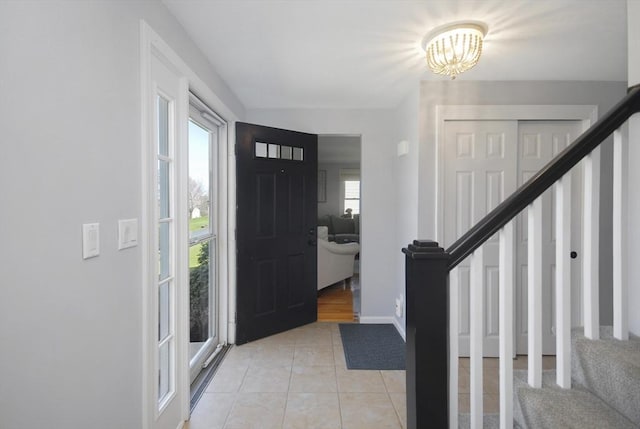 entryway featuring stairs, baseboards, a notable chandelier, and light tile patterned floors