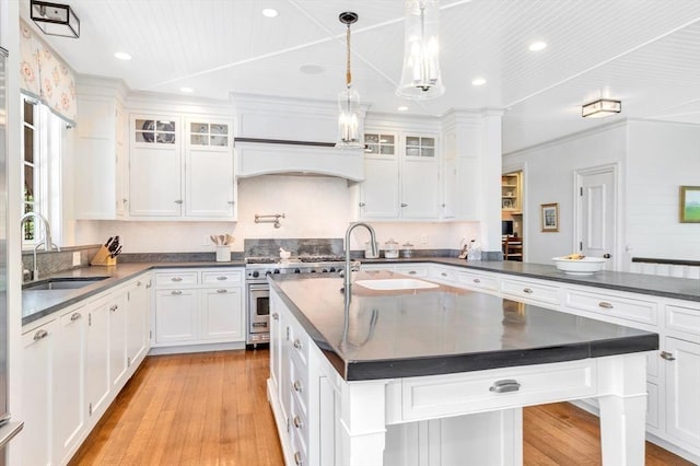 kitchen featuring white cabinets, an island with sink, and sink