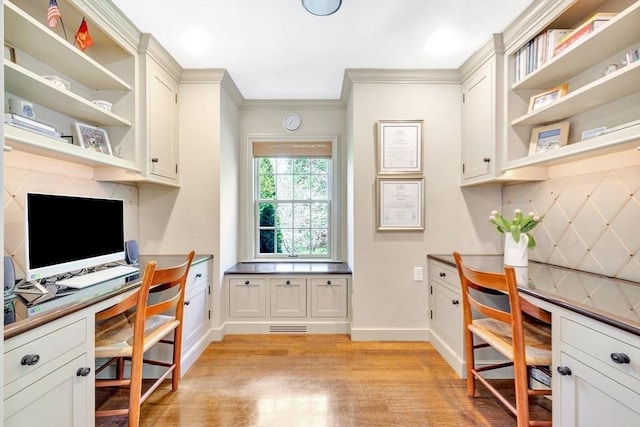 office space with light hardwood / wood-style floors, built in desk, and ornamental molding