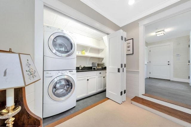 clothes washing area with ornamental molding, stacked washer / drying machine, and sink