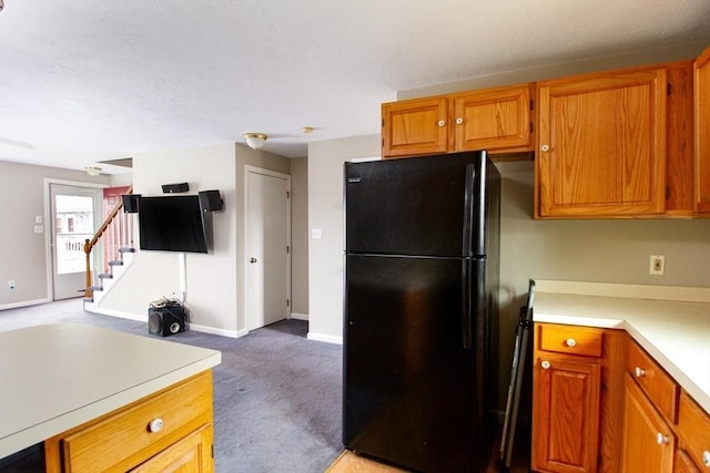 kitchen featuring light colored carpet and black fridge