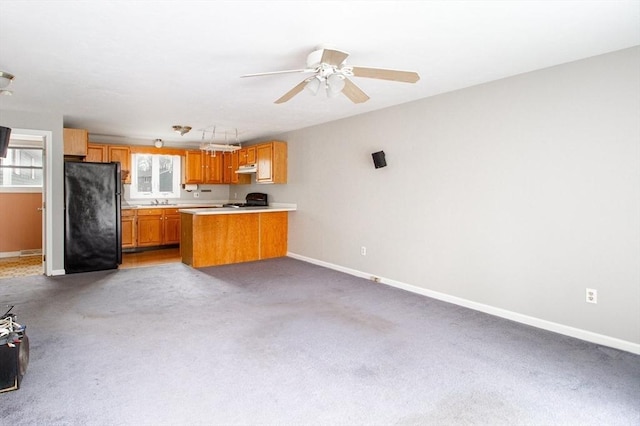 kitchen featuring ceiling fan, black refrigerator, range, and kitchen peninsula