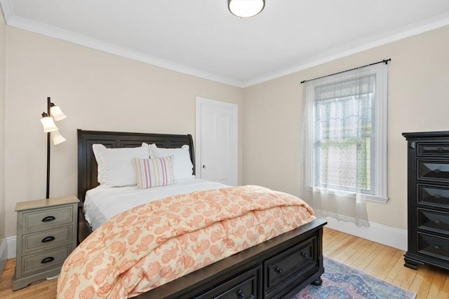 bedroom featuring baseboards, crown molding, and light wood finished floors