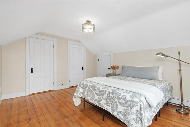 bedroom with baseboards, vaulted ceiling, and hardwood / wood-style flooring