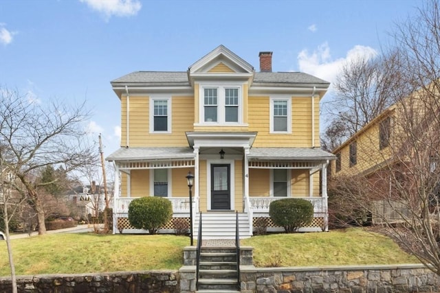 view of front of house featuring a porch, a chimney, a front yard, and a shingled roof