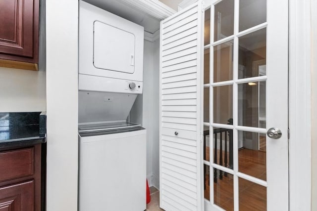 laundry area featuring stacked washer / dryer, french doors, and laundry area