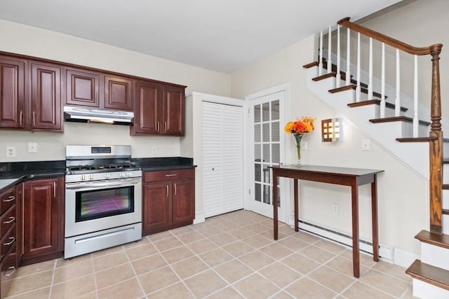 kitchen featuring stainless steel gas range oven, under cabinet range hood, a baseboard heating unit, dark countertops, and light tile patterned flooring