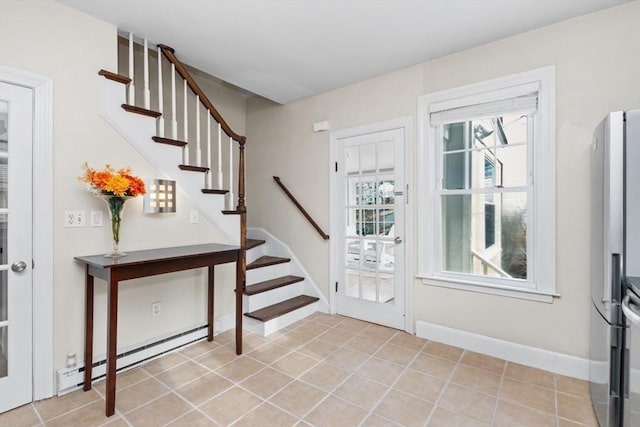 entrance foyer featuring light tile patterned floors, a baseboard heating unit, baseboards, and stairs