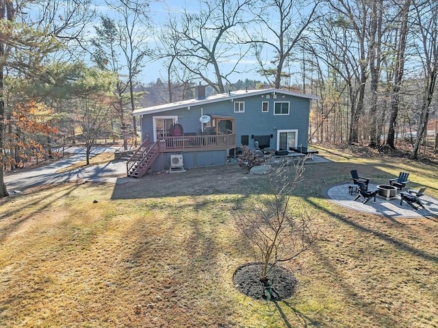 rear view of house featuring a wooden deck, a fire pit, a lawn, and a patio