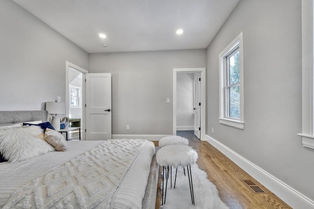 bedroom featuring baseboards, visible vents, wood finished floors, and recessed lighting