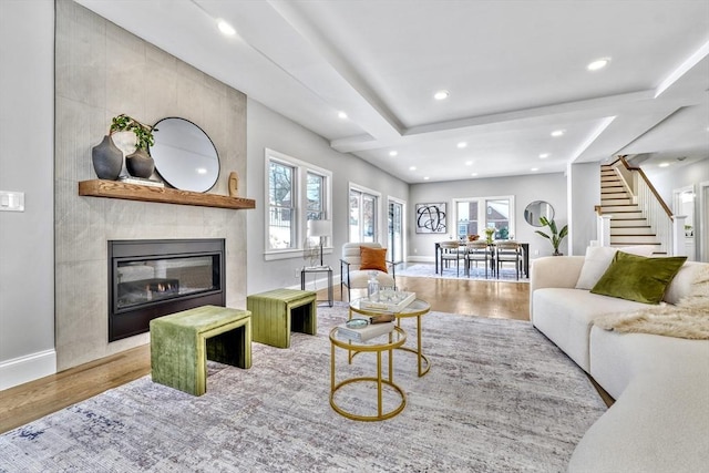 living area featuring baseboards, stairway, wood finished floors, a fireplace, and recessed lighting