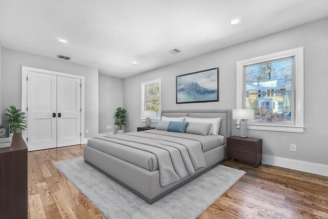 bedroom with a closet, light wood-type flooring, visible vents, and baseboards