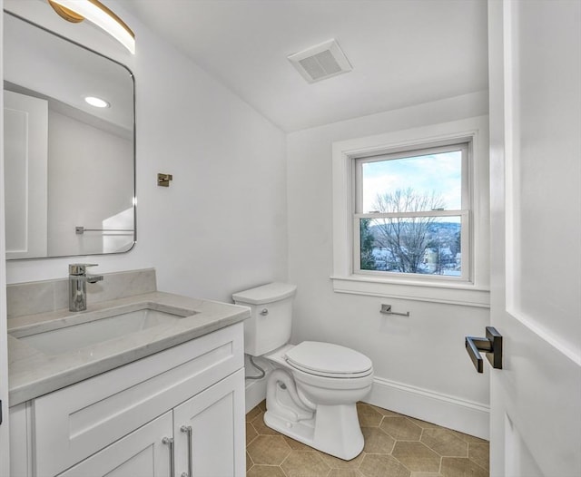 half bathroom featuring visible vents, toilet, vanity, baseboards, and tile patterned floors