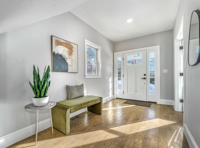 entryway featuring lofted ceiling, wood finished floors, visible vents, and baseboards