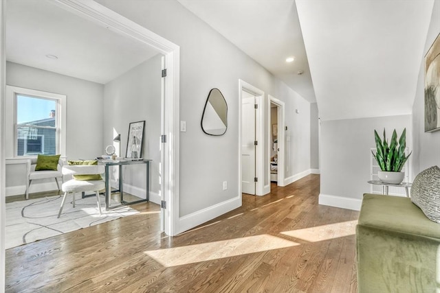 interior space with vaulted ceiling, baseboards, and wood finished floors