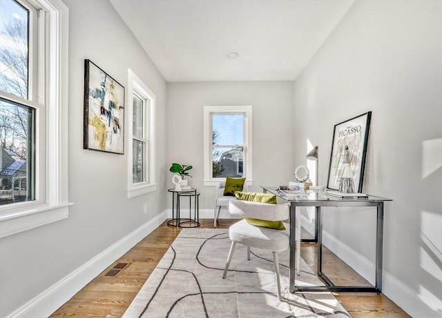 office area featuring light wood-type flooring, visible vents, and baseboards