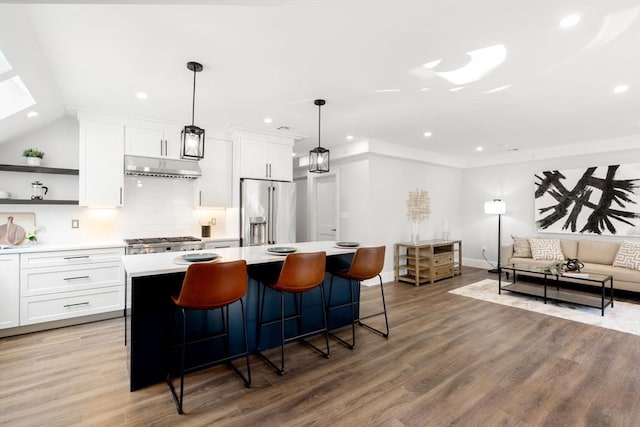 kitchen with high quality fridge, white cabinetry, a kitchen island, and hardwood / wood-style flooring