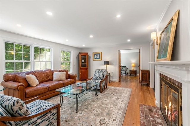 living room featuring recessed lighting, baseboards, a fireplace, and light wood finished floors