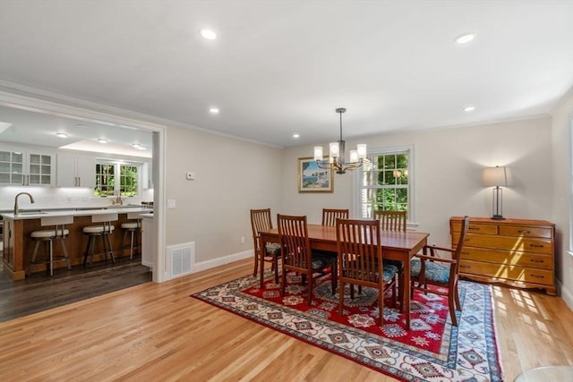 dining room featuring light wood-style flooring, crown molding, and an inviting chandelier